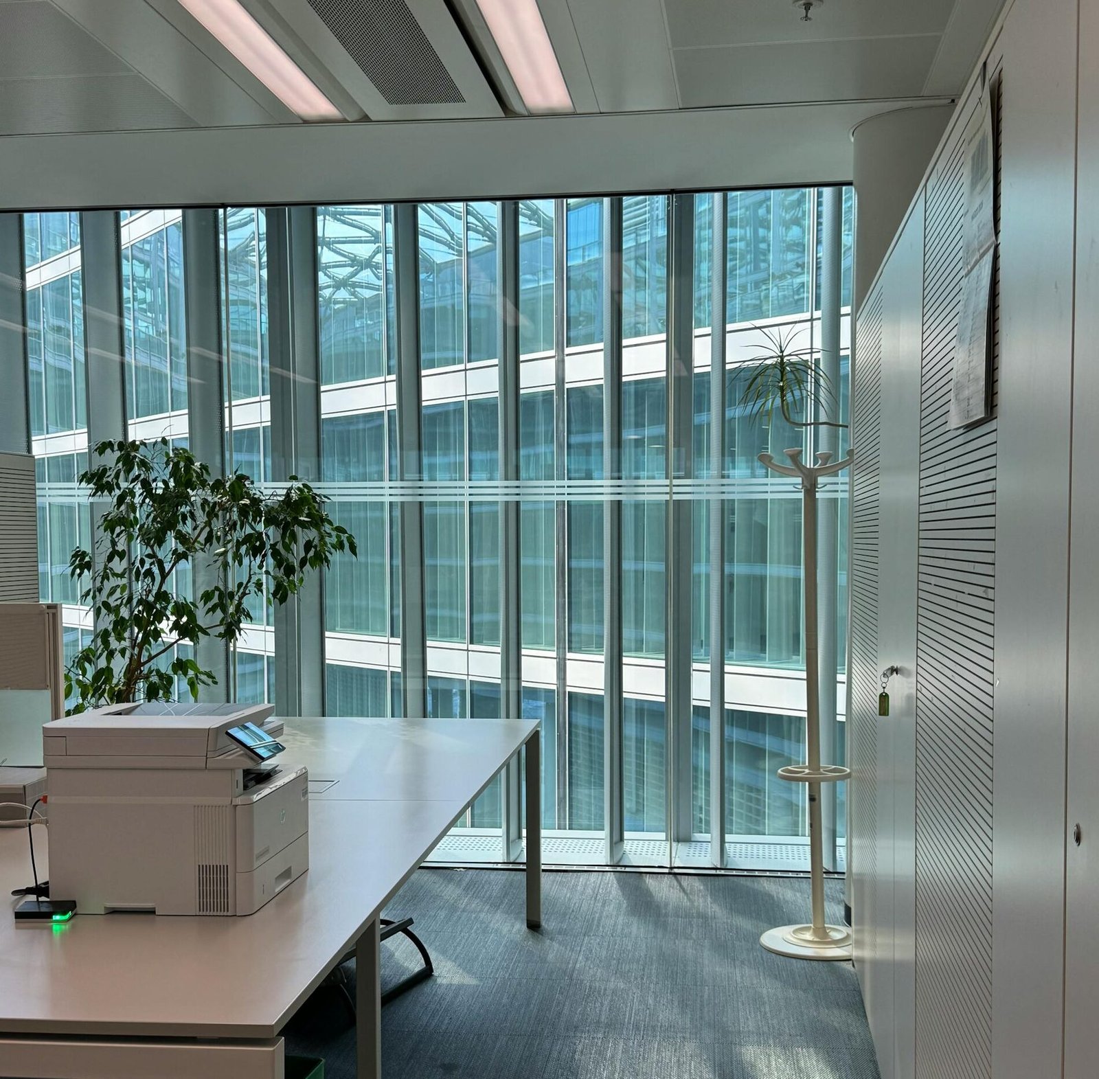 Bright office space in Milan featuring large windows, modern furniture, and natural lighting.
